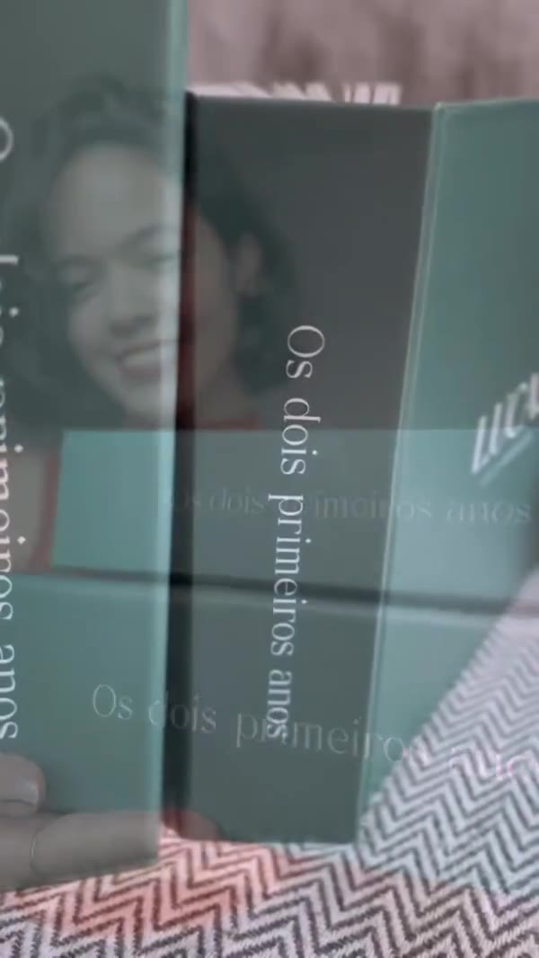 Álbum impresso ‘Os dois primeiros anos’, com capa de linho, sendo folheado.
